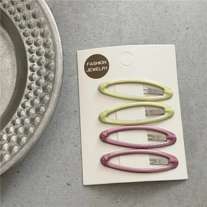 Close-up of four marble-textured oval BB hair clips in pink and green on a display card