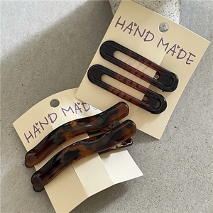 Detail view of tortoiseshell acetate hair clips on a handmade card with stone background
