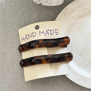Detail of tortoise shell duckbill hair clips with leopard print pattern on display card