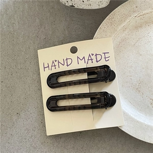 Close-up of leopard pattern duckbill hair clips on card over a textured stone base