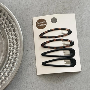 Close-up of leopard pattern and black hair clips on a white display card base