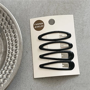 Set of four glossy black leopard style hair clips on card over gray textured surface