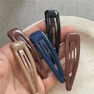 Set di cinque fermagli per capelli a goccia in metallo opaco colorato tenuti in mano