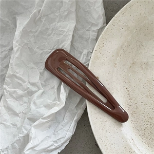 Dettaglio del fermaglio BB a goccia in metallo marrone cioccolato con finitura lucida a olio