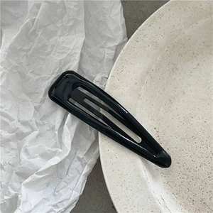 Dettaglio di un fermaglio per capelli a goccia nero lucido su un piatto in ceramica