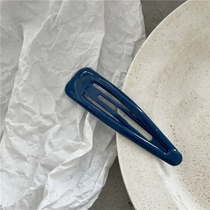 Vista ravvicinata di un fermaglio per capelli blu scuro lucido su un piatto di ceramica