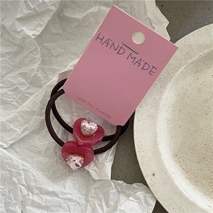 Détail de chouchous cœur en cristal rose avec élastiques et emballage artisanal fait main