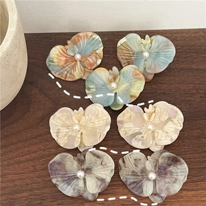 Detailed macro view of acetate orchid hair clips with marble texture and pearl centers