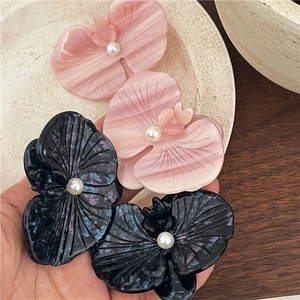 Close-up of elegant acetate orchid hair clips with pearls in pink and navy blue colors