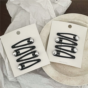 Detail of black drip oil BB clips with silver beads on a white card display
