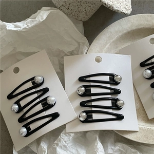 Close-up of black teardrop hair clips with silver bead accents on white cards