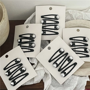 Close-up of black drip oil teardrop hair clips with silver beads on display cards