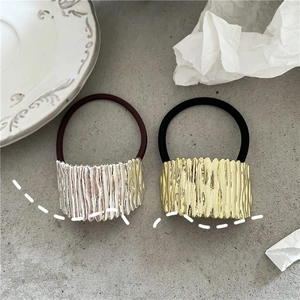 Close-up of gold and silver ponytail holders with liquid metal ripple texture