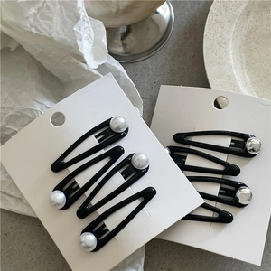 Detail of black metal waterdrop hair clips with silver beads on white card packaging