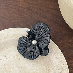 Close-up of elegant black marble texture acetate orchid hair clip with pearl center