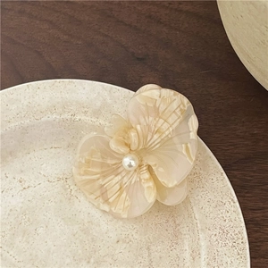Macro view of acetate orchid hair clip with marble texture and pearl centerpiece