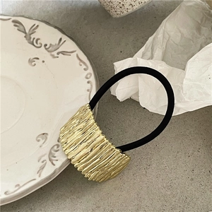 Detailed close-up of a gold-plated vintage hair tie with elegant vertical pleat texture