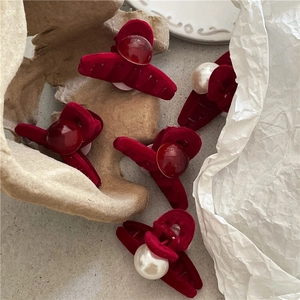 Detailed view of red velvet mini hair claws featuring faux pearls and vintage flocking texture