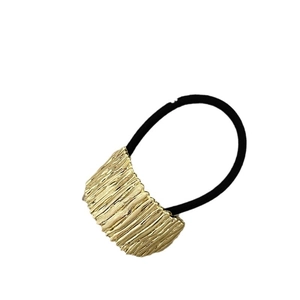 Vintage style gold textured metal ponytail holder with black elastic hair tie on white background