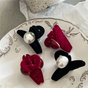 Detailed view of four flocked hair clips with pearls and beads on a white ceramic plate