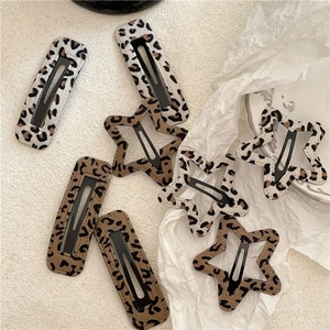 Set of leopard print star and rectangular hair clips on elegant textured stone background