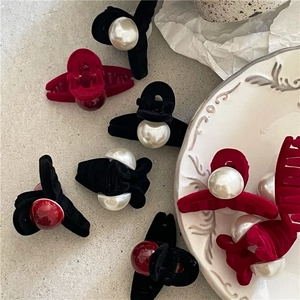 Velvet mini hair claw clips with faux pearl and red beads set on elegant textured surface