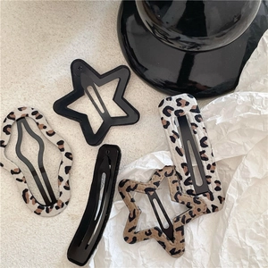 Detail shot of leopard print and black star-shaped BB hair clips on a textured surface