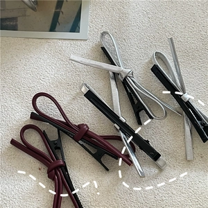 Détails de pinces à cheveux noeud en cuir PU argent et bordeaux sur fond texturé