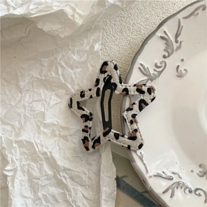 Detail of star-shaped hair clip with leopard print fabric and black metal frame