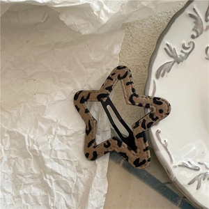 Detail shot of a star-shaped leopard print hair clip on a vintage decorative porcelain plate