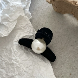 Detail of a mini black flocked hair claw clip with a large white imitation pearl accent