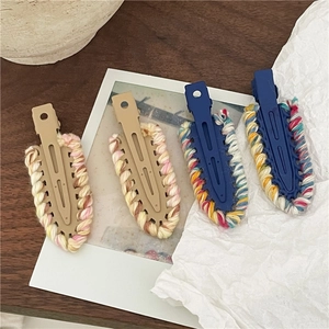 Detailed view of four colorful knitted teardrop hair clips on a cozy wooden background