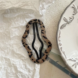 Macro shot of wavy leopard print fabric BB hair clip on a minimalist white plate