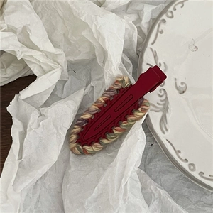 Macro detail of red matte duckbill clip with colorful hand-woven yarn border textures