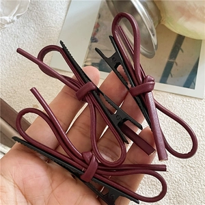 Détail des barrettes nœuds en cuir PU bordeaux avec texture sur base métallique noire mate