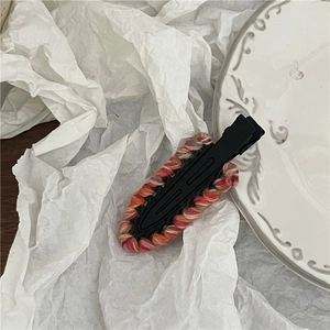 Detail of colorful knitted yarn hair clips on a ceramic plate with soft shadows