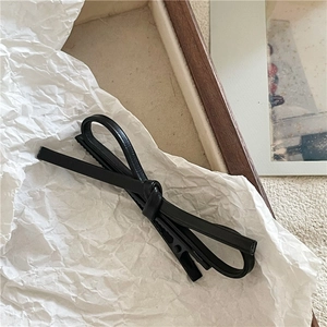 Détail d'un nœud papillon en cuir PU noir avec une texture gaufrée sur une pince à cheveux