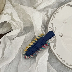 Close-up of dark blue hair clip featuring colorful hand-knitted yarn edges for women