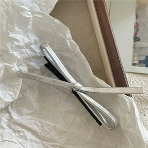 Gros plan d'une pince à cheveux nœud argenté avec clip bec de canard sur papier blanc
