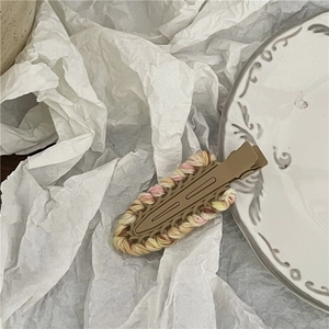 Detail of hand-woven wool hair clip in yellow and pink colors with brown base