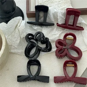 Dettaglio di fermagli per capelli a fiore e fiocco in resina nera e rosso vino con molle