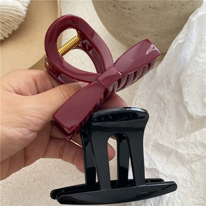 Dettaglio molletta per capelli a fiocco bordeaux e classica clip nera a mano