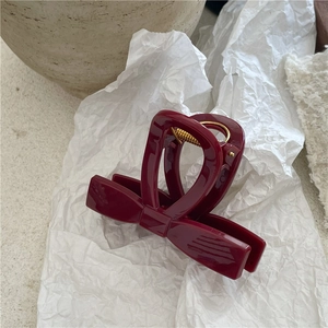 Dettaglio di un fermaglio per capelli a fiocco bordeaux su carta bianca spiegazzata
