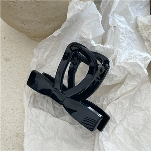 Dettaglio di un fermaglio per capelli nero lucido a forma di fiocco con molla in metallo