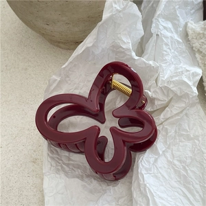 Dettaglio della pinza per capelli a farfalla rosso vino con finitura lucida
