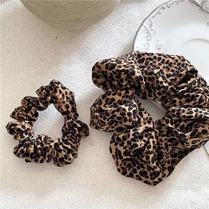 Detail of two sizes of leopard print hair scrunchies with soft pleated fabric texture