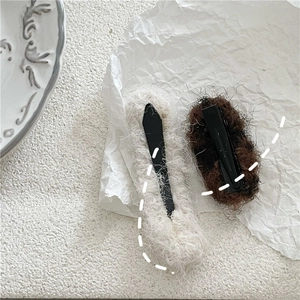 Detail of plush beige rectangular and dark brown oval hair clips on white paper