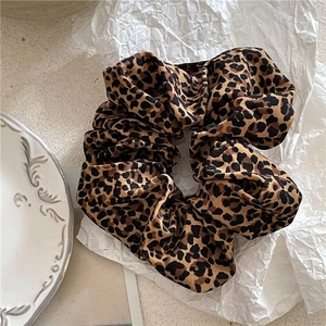 Detail of leopard print fabric scrunchie with soft pleats on a white background