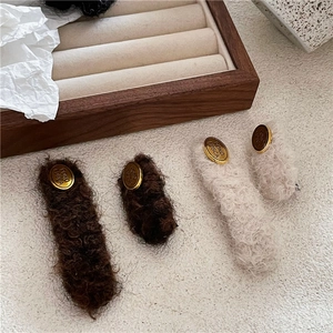 Detail view of plush fabric hair clips with gold oval metal plate and engraved lettering