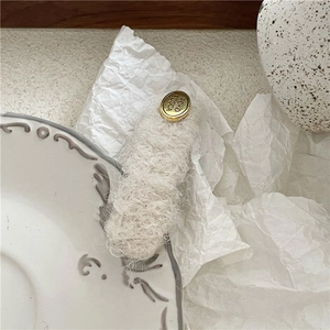 Detail of plush off-white mohair hair clip with engraved gold oval metal buckle
